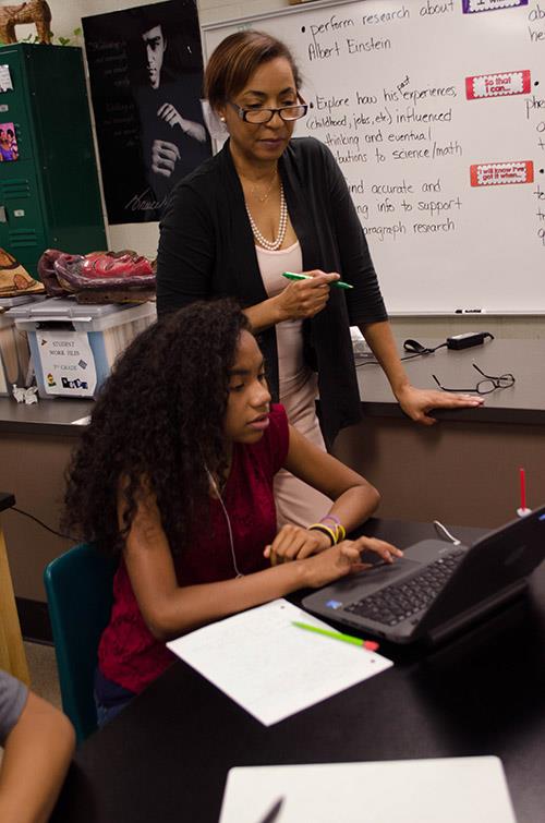 Teacher watching student work on laptop